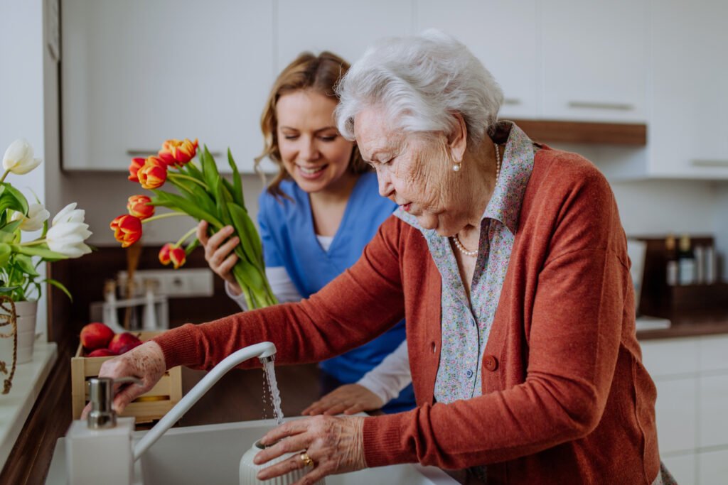 Haushaltshilfe in Bochum unterstützt eine Seniorin beim Blumenarrangieren in der Küche